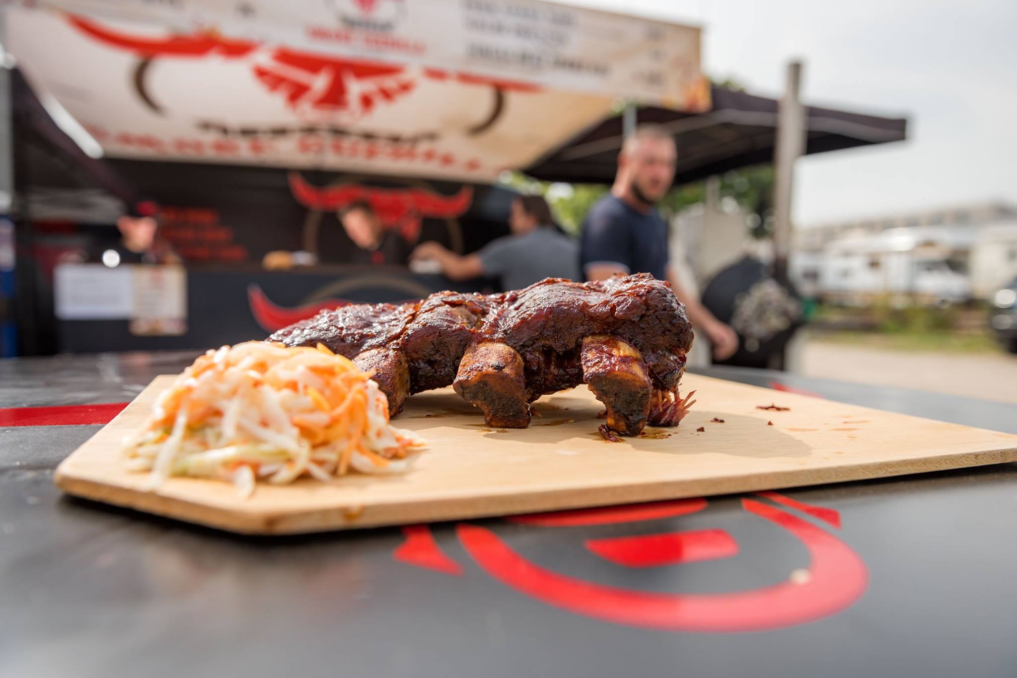 Beef Ribs mit Coleslaw auf einem Holzbrett vor dem BBQ-Stand